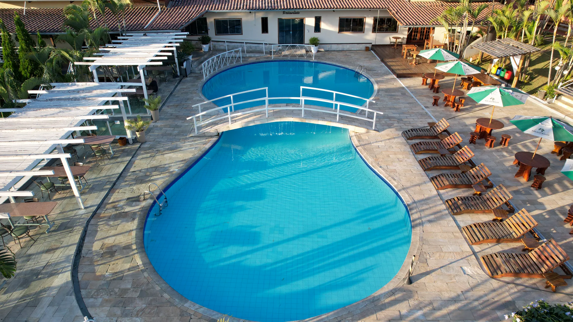 Piscina central ao ar livre do Hotel Gran Minas, com espreguiçadeiras e o restaurante ao fundo